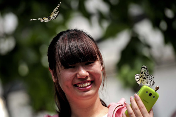 Lundi, une femme s'amuse avec les papillons du Jardin botanique de Beijing. [Photo/Asianewsphoto]