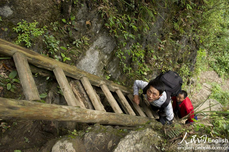 Le 11 avril 2013, un journaliste d'un journal local emprunte une échelle pour pouvoir accéder au village de Zhangjiawan dans le district du Sangzhi de la province chinoise du Hunan. (Photo : People's Daily Online)