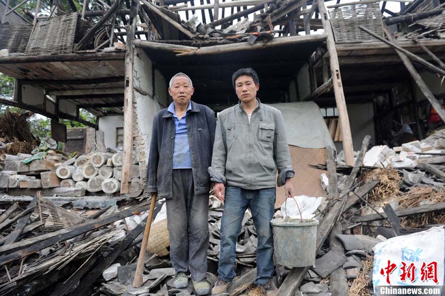 Deux habitants du bourg Longquan devant leur maison dévastée dans un séisme de magnitude 7,0 survenu dans le district de Lushan de la ville de Ya'an, dans la province du Sichuan, le 20 avril 2013.