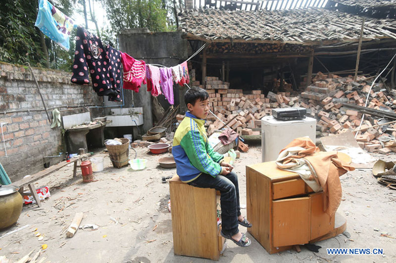 Une garçon du bourg Longquan devant sa maison dévastée dans un séisme de magnitude 7,0 survenu dans le district de Lushan de la ville de Ya'an, dans la province du Sichuan, le 20 avril 2013. 