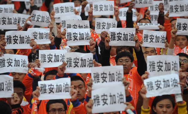 Les spectateurs brandissent des bannières où l’on peut lire « Courage, Ya'an ! », pour les habitants de la zone sinistrée lors d'un match de football de la Super League chinoise dans la ville de Jinan, dans la Province du Shandong, dans l’Est de la Chine, le 20 avril 2013. [Photo / Xinhua]