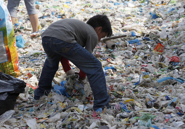 Un étudiant ramasse des déchets pour nettoyer le littoral de la zone d’habitation et d’écotourisme de Paranaque, incluant une forêt de mangroves et un sanctuaire d'oiseaux, dans le cadre de la commémoration de la journée de la Terre à Manille, le 20 avril 2013. [Photo/agences]