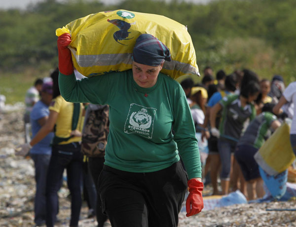 L'Américaine missionnaire Rebecca Lawson, venue de Pennsylvanie, porte un sac d'ordures après avoir réuni des étudiants, activistes environnementaux et bénévoles pour nettoyer le littoral de la zone d'habitation et d'écotourisme de Paranaque, incluant un forêt de mangroves et un sanctuaire d'oiseaux, dans le cadre de la commémoration de la journée de la Terre à Manille, le 20 avril 2013. [Photo/agences]
