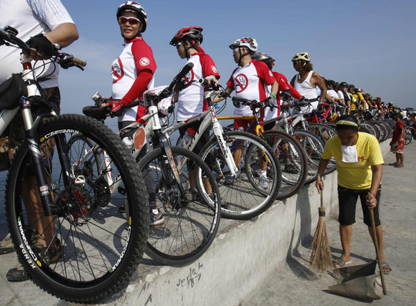 Un groupe de cyclistes avec leurs vélos alignés sur un mur bordant la mer, pour prendre part à l'événement « Sauver la baie de Manille» lors des célébrations de la Journée de la Terre à Manille, le 21 avril 2013. [Photo/agences]