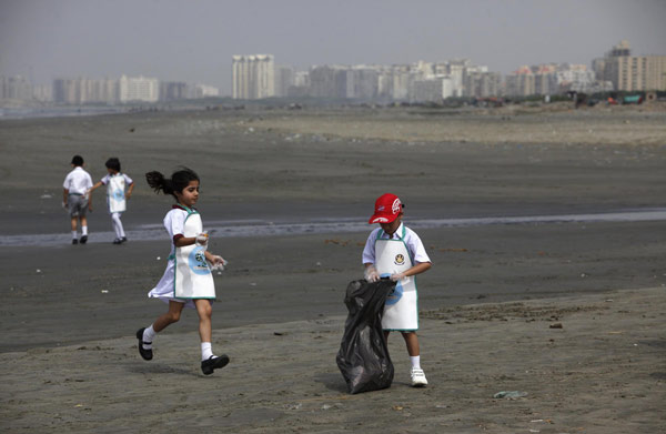 Au petit matin, des écoliers ramassent des ordures se trouvant sur la plage de Clifton à Karachi, le 22 Avril 2013, à l'occasion d'une campagne de nettoyage dans le cadre de la commémoration de la Journée de la Terre. [Photo/agences]