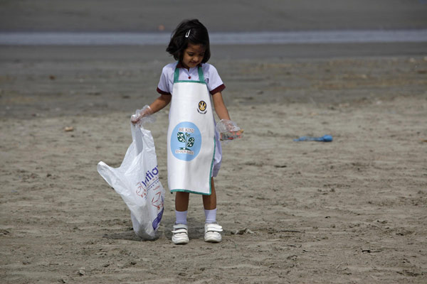 Au petit matin, une écolière ramasse des détritus sur la plage de Clifton à Karachi, le 22 Avril 2013, à l'occasion d'une campagne de nettoyage dans le cadre de la commémoration de la Journée de la Terre. [Photo/agences]