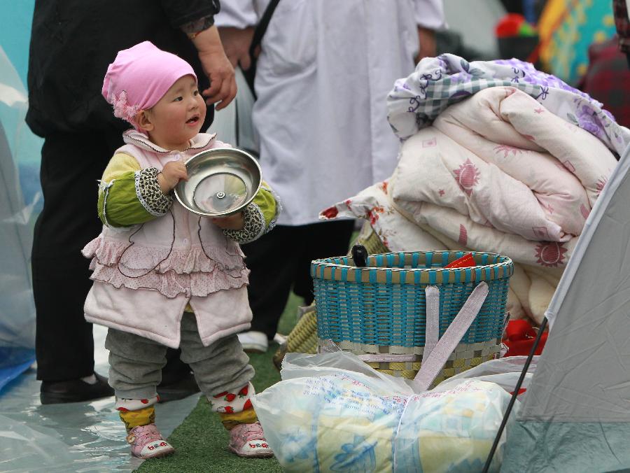 Le 22 avril 2013, Wang Xiuhan, une fillette d'un an et demi attend son repas dans un camp d'abris de sinistrés à Baoxing, un comté de la province chinoise du Sichuan qui a été frappée le 20 avril par un tremblement de terre de magnitude 7. (Photo : Xinhua/Pei Xin)