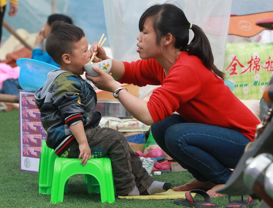 Le 22 avril 2013, une femme nourrit son fils dans un camp d'abris de sinistrés à Baoxing, un comté de la province chinoise du Sichuan qui a été frappée le 20 avril par un séisme de magnitude 7. (Photo : Xinhua/Pei Xin)