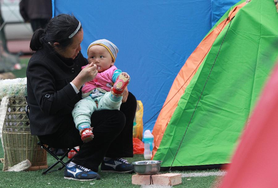 Le 22 avril 2013, une femme nourrit son petit-fils dans un camp d'abris de sinistrés à Baoxing, un district de la province chinoise du Sichuan qui a été frappée le 20 avril par un séisme de magnitude 7. (Photo : Xinhua/Pei Xin)