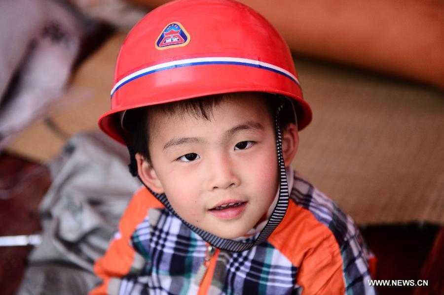 Un casque sur la tête, le petit garçon Hu Hanwei âgé de 4 ans reste dans une tente d'un camp d'abris temporaire de sinistrés à Lushan, un comté de la province du Sichuan frappé par un tremblement de terre de magnitude 7, samedi 20 avril 2013. (Photo : Xinhua/Zhang Hongxiang)