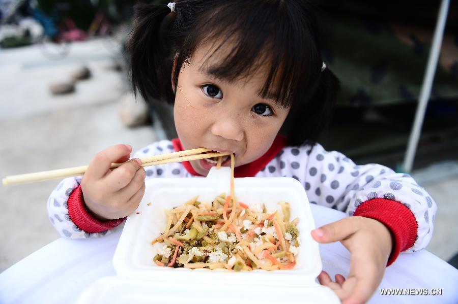 Du Xinrui, une fillette de 4 ans prends son repas dans un camp d'abris temporaire de sinistrés à Lushan, un comté de la province du Sichuan frappé par un tremblement de terre de magnitude 7, samedi 20 avril 2013. (Photo : Xinhua/Zhang Hongxiang)