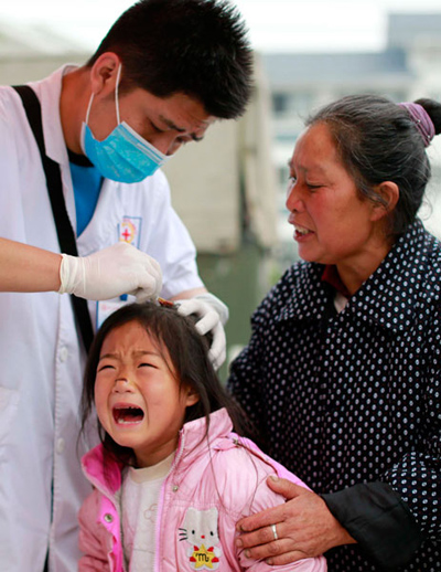 Wang Yuntian, une fillette de 7 ans, est soignée par le docteur Chai Yuan après le séisme meurtrier de samedi dans le canton de Longmen, province du Sichuan. De gros efforts sont déployés dans la zone du séisme pour maintenir les survivants en bonne santé. Feng Yongbin/China Daily
