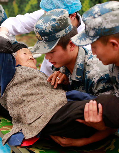  Lundi, des secouristes transportent Chen Guizhen,94 ans, vers une zone de sécurité dans de village de Qinglongchang du comté de Lushan, dans la province du Sichuan. Ce village a été l'une des zones les plus durement touchées par le tremblement de terre de magnitude 7, qui a eu lieu samedi.  Feng Yongbin/China Daily