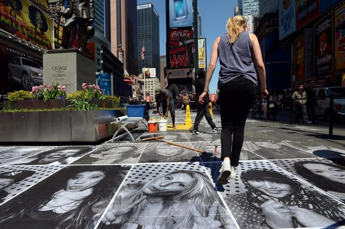 Une bénévole pose une photo par terre à Time Square à New York, le 25 avril 2013. L'exposition artistique composée des dizaine de milliers de portraits de passants posés par terre visait à attirer l'attention sur le multiculturalisme et le statut mondial de New York. [Photo / Xinhua ]