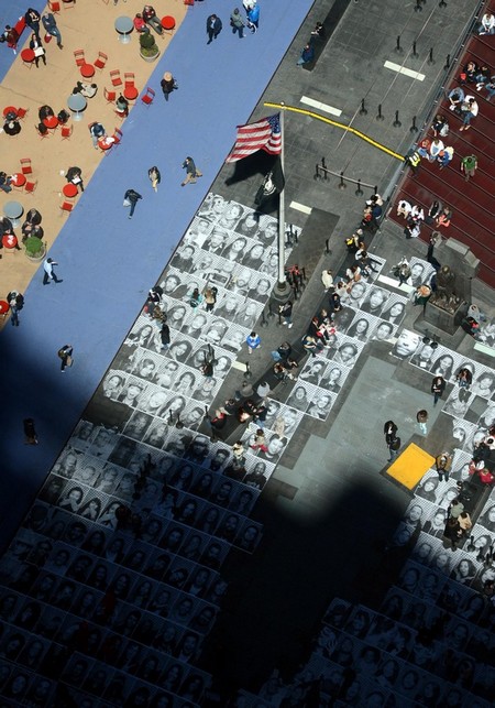 Les piétons marchent sur des portraits des gens posés par terre à Time Square à New York le 25 avril 2013. L'exposition artistique composée des dizaine de milliers de portraits de passants posés par terre visait à attirer l'attention sur le multiculturalisme et le statut mondial de New York. [Photo / Xinhua ]