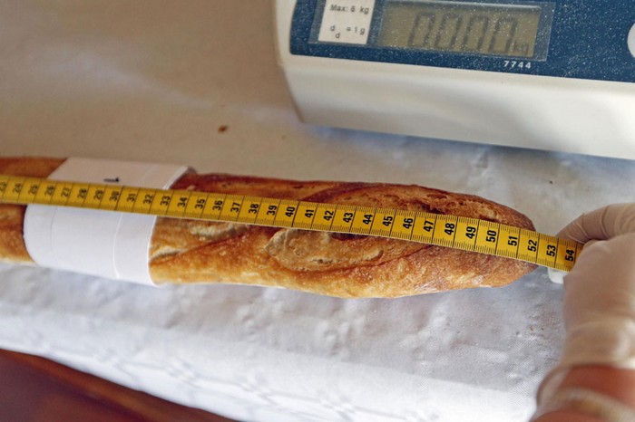 Un assistant mesure une baguette enregistrée pour la compétition pour le prix annuel «Grand Prix de la Baguette de la Ville de Paris» (meilleure baguette de Paris 2013) à la Chambre Professionnelle des Artisans Boulangers Pâtissiers à Paris, le 25 avril 2013. [Photo/agences]