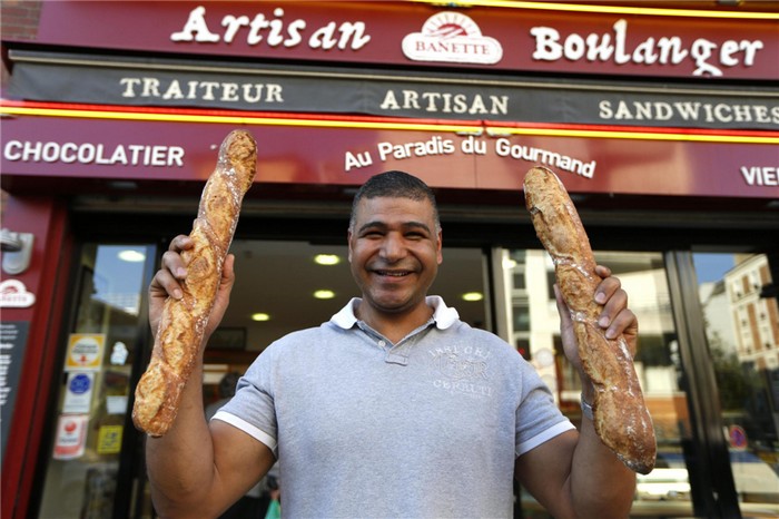 Le boulanger parisien Ridha Khadher, vainqueur du Prix de la meilleure baguette de Paris 2013, pose devant sa boulangerie avec ses baguettes après le verdict à Paris, le 25 avril 2013. [Photo/agences]