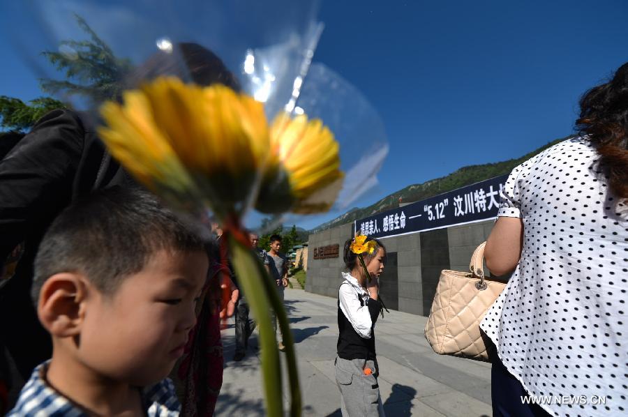Le 12 mai 2013, dans le bourg de Yingxiu du district de Wenchuan dans le Sichuan, des enfants, une fleur à la main, ont rendu hommage aux victimes du séisme d'une magnitude de 8.0 qui a frappé la régions il y a cinq ans. (Photo : Xinhua/Bai Yu)