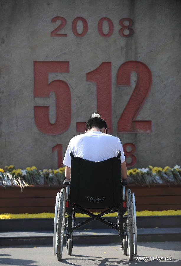 Un jeune homme en fauteuil roulant, qui a perdu ses jambes dans le séisme du Wenchuan il y a cinq ans, a tenu à rendre hommage aux victimes de la catastrophe devant un monument commémoratif à Beichuan dans la province du Sichuan, le 12 mai 2013. 