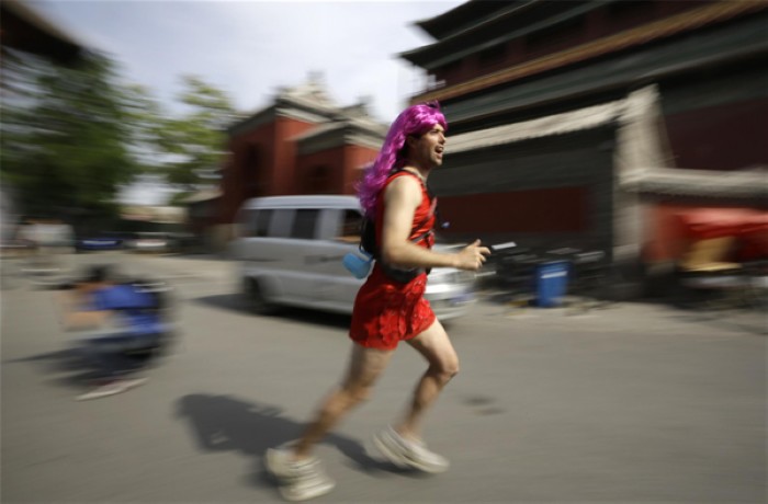 Un coureur portant une robe rouge passe, passe devant la Tour du Tambour de Beijing, lors de l'événement de charité, la Red Dress Run, à l'occasion de la Fête des Mères, le 12 mai 2013. [Photo/agences]