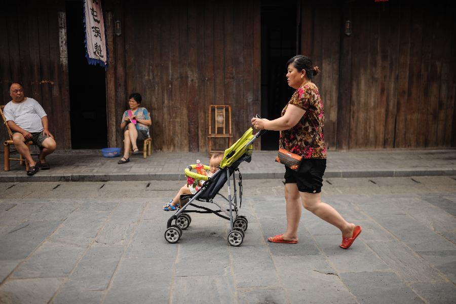 Une femme se promène avec un bébé dans une rue d'Anren, une ville ancienne du Comté de Dayi, à Chengdu, capitale de la Province du Sichuan, dans le Sud-ouest de la Chine, le 23 mai 2013.