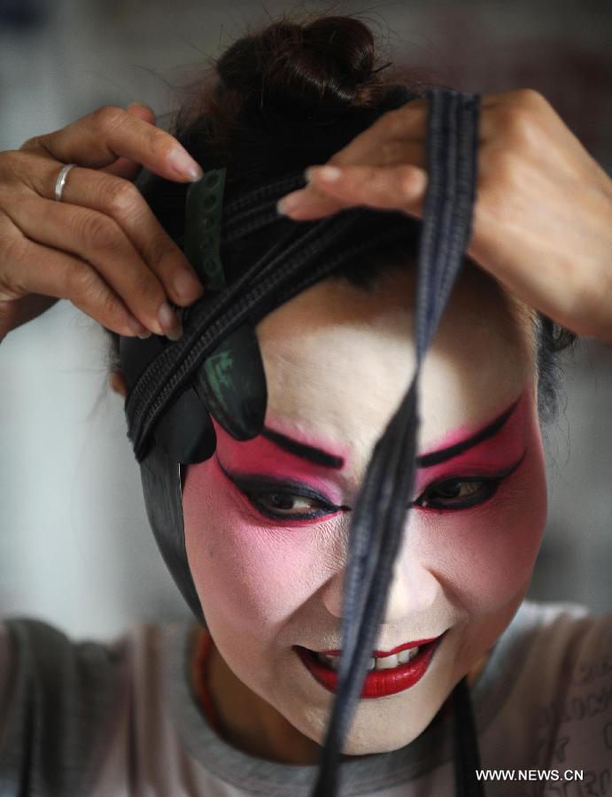 Le 1er juin 2013, au Jardin des Chen dans la banlieue de Chengdu, la province du Sichuan, une actrice de la Troupe de l'opéra du Sichuan prépare les costumes en coulisse. (Xinhua/Xue Yubin)