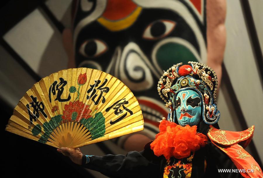 Sur cette photo d'archive, prise le 19 août 2013 au Musée du Temple Wuhuo à Chengdu, la capitale de la province du Sichuan, un acteur de l'opéra du Sichuan opère un changement de masques sur scène. (Xinhua/Xue Yubin)