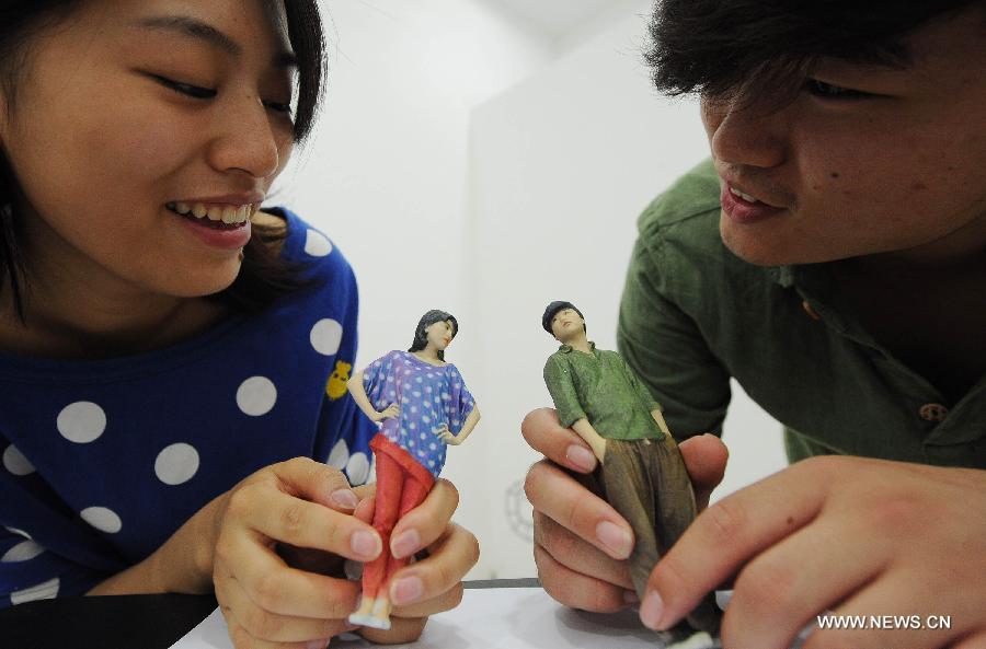 Un jeune couple regarde des figurines imprimées en 3D d'eux-mêmes dans une boutique d'impression 3D qui vient d'ouvrir dans la municipalité de Chongqing, dans le Sud de la Chine, le 3 juin 2013. [Photo / Xinhua]