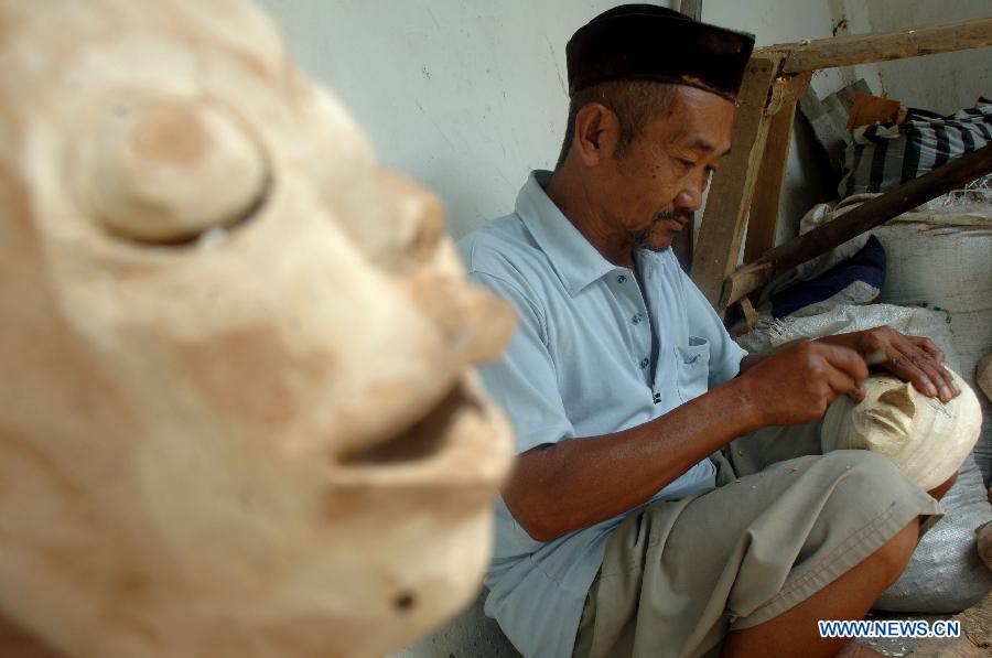 Un homme polit un Topeng Malang, ou le masque de Malang, dans un atelier de masque à Malang, dans l'est de Java, en Indonésie, le 6 juin 2013. (Xinhua/Hidayat)