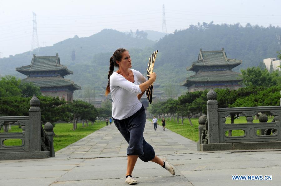 Une apprenante étranger s'échauffe avant de pratiquer les arts martiaux chinois au Palais Yuxu, sur le Mont Wudang, connu pour être un centre traditionnel de l'enseignement et de la pratique des arts martiaux, dans la Province du Hubei, dans le Centre de la Chine, le 5 juin 2013. [Photo / Xinhua]