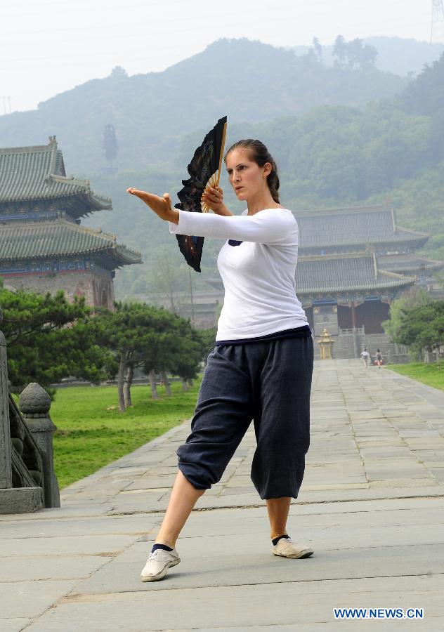 Une apprenante étranger s'échauffe avant de pratiquer les arts martiaux chinois au Palais Yuxu, sur le Mont Wudang, connu pour être un centre traditionnel de l'enseignement et de la pratique des arts martiaux, dans la Province du Hubei, dans le Centre de la Chine, le 5 juin 2013. [Photo / Xinhua]