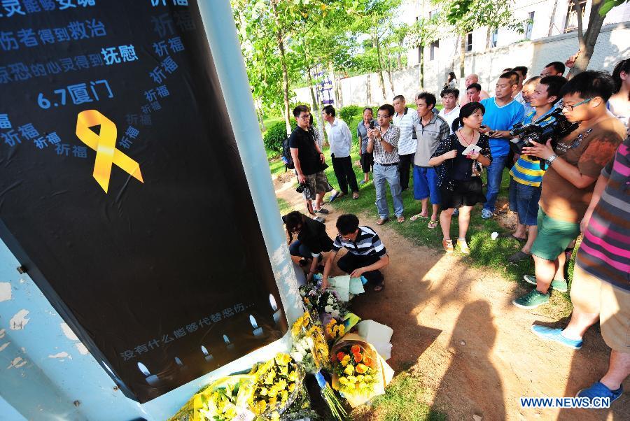 Des gens déposent des fleurs en hommage aux victimes devant une borne de la ligne de bus où un incendie de bus a eu lieu vendredi, à Xiamen, dans la Province du Fujian, dans le Sud de la Chine, le 8 juin 2013. L'incendie du bus a coûté la vie à 47 personnes et 34 autres ont été hospitalisées. Photo : Xinhua