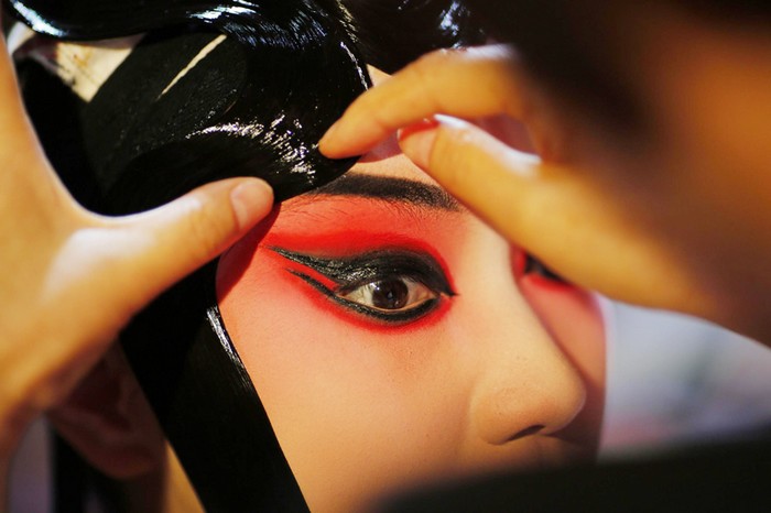 Une artiste prise en photo alors qu'elle applique son maquillage avant une avant-première d'un spectacle d'Opéra de Pékin réservée aux médias, au musée des textiles de Shanghai, le 8 juin 2013.