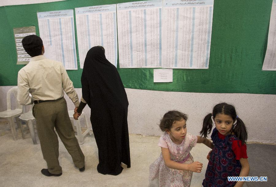 Deux petites filles s'amusent à un bureau de vote dans le nord de Téhéran, en Iran, le 14 juin 2013. Le dirigeant suprême de l'Iran, l'ayatollah Ali Khamenei, a voté à l'élection présidentielle iranienne et déclaré l'ouverture du scrutin vendredi matin. (Photo: Xinhua/Ahmad Halabisaz) 
