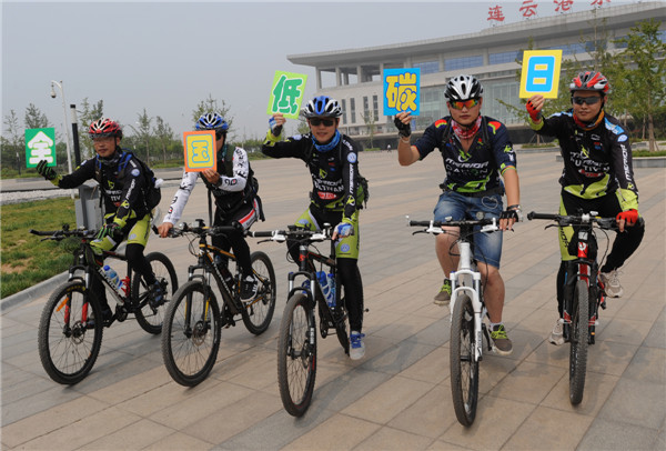 Des bénévoles vont à vélo pour promouvoir la première Journée Nationale du Bas Carbone de Chine à Lianyungang, dans la Province du Jiangsu, le 16 juin 2013. La Journée Nationale du Bas Carbone a eu lieu cette année le 17 juin 2013, sur le thème « Ayez une attitude pauvre en carbone et construisez de belles maisons ». [Photo Geng Yuhe / Asianewsphoto]