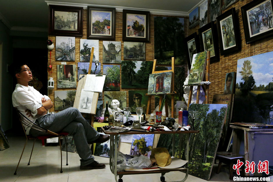 Fucha Danqing dans son studio. Sur le mur sont accrochées ses peintures.