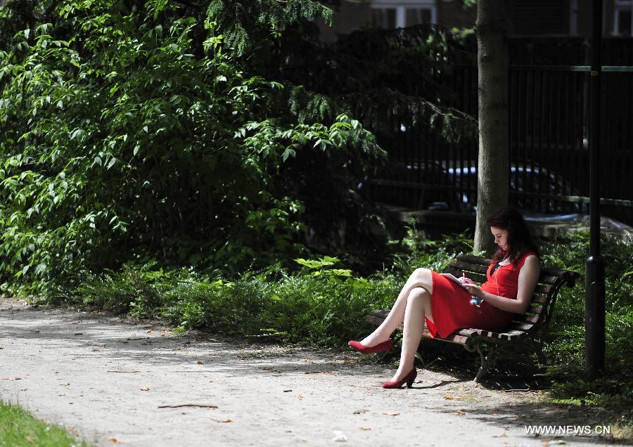 Une jeune femme étudie dans un parc près de l'Université catholique de Louvain, à Louvain, en Belgique, le 18 juin 2013. La température a atteint 31°C, la plus haute depuis cette année, suivi d'un hiver et printemps aussi froid et humide. (Xinhua/Ye Pingfan)