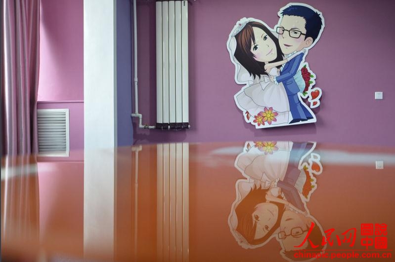 Sur le mur de la chambre est suspendue l'image humoristique d'un couple d'amoureux