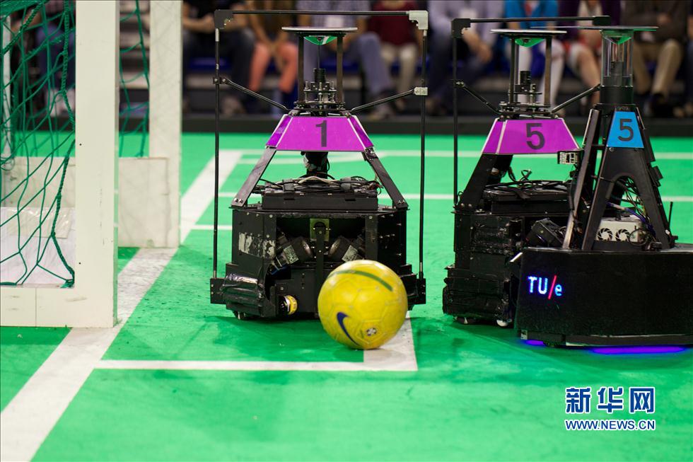 Le 30 juin à Eindhoven, aux Pays-Bas, l'« Équipe de l'eau » (en violet) de l'Université des Sciences et Technologies de l'Information de Beijing se défend contre l'équipe néerlandaise d'Eindhoven « Tech United » (en bleu) aux Pays-Bas lors de la compétition de football pour robots RoboCup.
