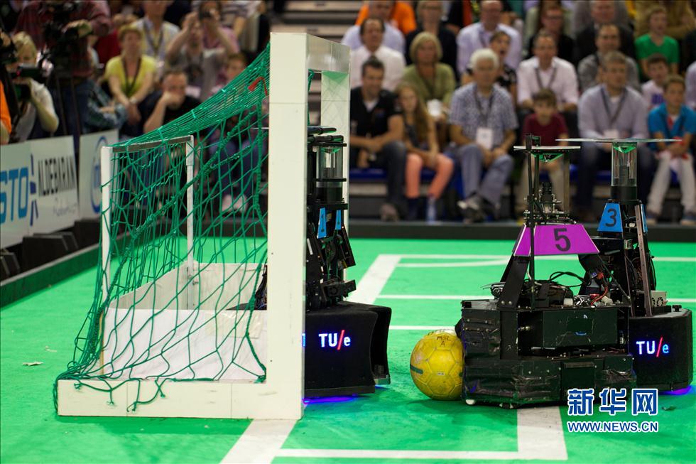 A Eindhoven, aux Pays-Bas, un robot de l'« Équipe de l'eau » (en violet) de l'Université des Sciences et Technologies de l'Information de Beijing tire au but face à l'équipe « Tech United » (en bleu) Tech Unies d'Eindhoven aux Pays-Bas lors de la finale de la compétition de football pour robots RoboCup .
