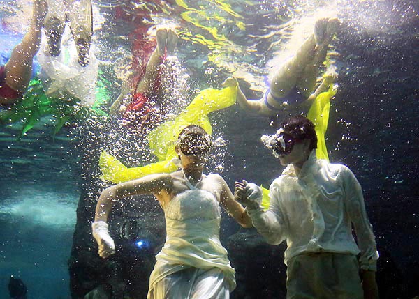 Des modèles portent des robes de mariée et costumes à un défilé de mode sous-marin à l'Aquarium de Zuohai à Fuzhou, dans la province du Fujian, le 17 juillet 2013. [Photo: Yang E'nuo/Asianewsphoto]