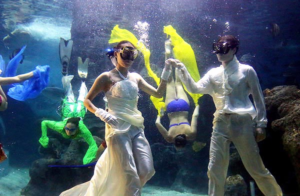 Les modèles présentent des robes de mariée et costumes à un défilé de mode sous-marin à Zuohai Aquarium de Fuzhou, province du Fujian, le 17 juillet 2013. [Photo: Yang E'nuo/Asianewsphoto]