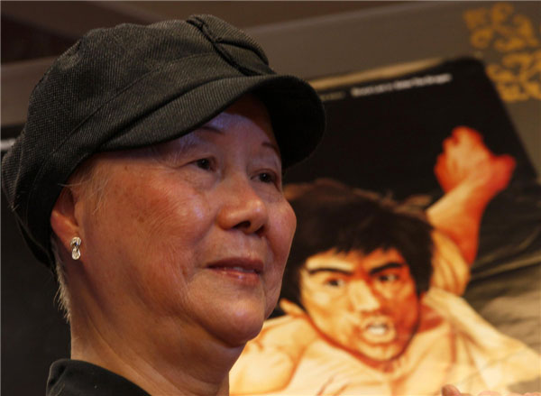 Le 18 juillet 2013 à Hong Kong, Phoebe Lee, la soeur aînée de Bruce Lee, pose avec une affiche de film de son frère lors d'une conférence de presse. [Photo : Agences]