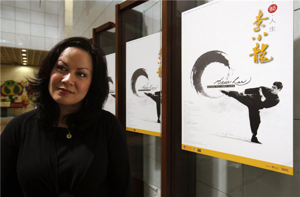 Le 18 juillet 2013 au Musée culturel de Hong Kong, Shannon Lee, fille de Bruce Lee, pose à côté d'une affiche de son père, lors de l'ouverture proche dans le musée d'une exposition consacrée à la star qui durera cinq ans. [Photo : Agences]