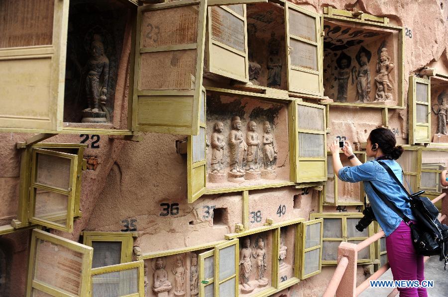 Le 17 juillet 2013, une touriste photographie des grottes du temple Bingling situées dans le district de Yongjing, la province du Gansu en Chine. [Photo: Xinhua]