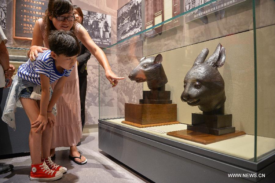 Les visiteurs admirent les têtes en bronze du rat et du lapin, données par la famille française Pinault en avril, exposées au Musée National de Chine à Beijing, capitale de la Chine, le 18 juillet 2013. [Photo / Xinhua]