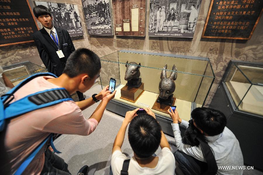 Les visiteurs prennent des photos des têtes en bronze du rat et du lapin, données par la famille française Pinault en avril, exposées au Musée National de Chine à Beijing, capitale de la Chine, le 18 juillet 2013. [Photo / Xinhua]