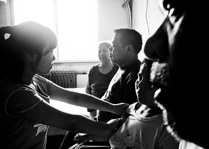 Gao Ran avec sa famille dans le District de Hexi à Tianjin, le 12 juillet 2013. Quatre des cinq membres de la famille ont perdu la vue, faisant de la jeune fille, la seule personne qui peut voir, l'espoir de toute la famille. Son grand-père et ses parents sont tous nés avec des troubles de la vision, tandis que sa grand-mère est devenue aveugle après une maladie. Elle doit prendre soin de toute la famille après que ses grands-parents et sa mère soient devenus handicapés après différentes maladies. [Photo Hu Lingyun / Asianewsphoto]