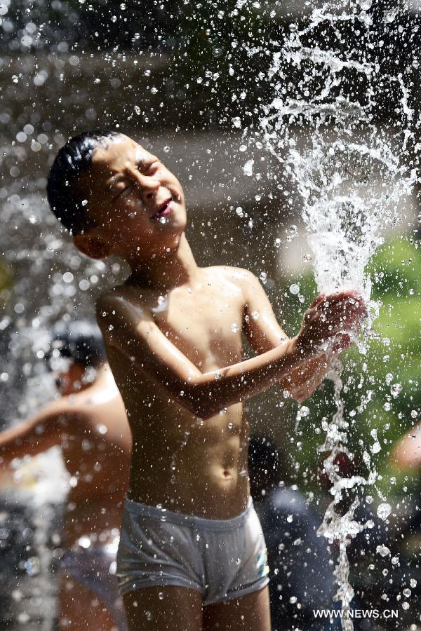 Un enfant se rafraîchit dans une fontaine à Hangzhou, capitale de la province du Zhejiang (est de la Chine), le 28 juillet 2013. Une vague de chaleur a frappé de nombreuses régions de la Chine ces derniers jours.