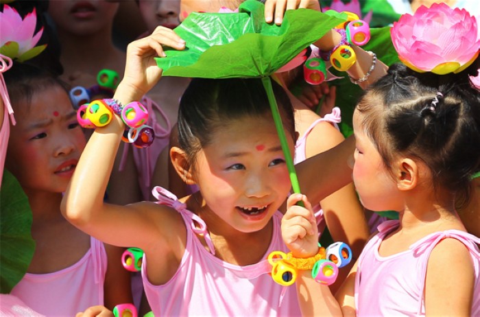 Des enfants se cachent sous un lotus, lors de la première édition du Festival des Lotus à Wufu, dans la ville de Wuyishan, dans la Province du Fujian, en Chine de l'Est, le 26 juillet 2013. Le festival durera jusqu'au 1er octobre. [Photo Zouhong / Asianewsphoto]